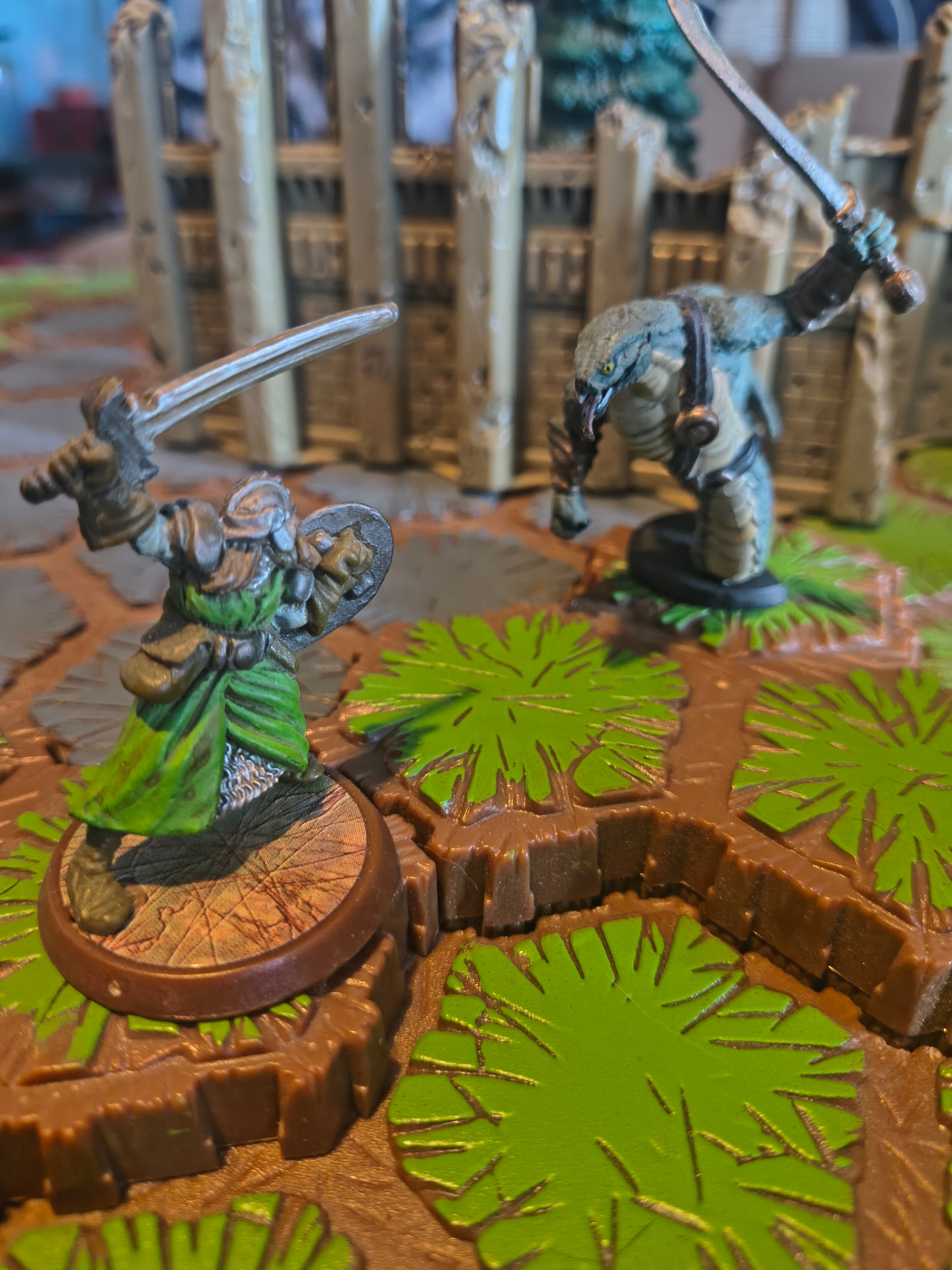 Two painted miniatures dueling with swords on a hex tile battlefield